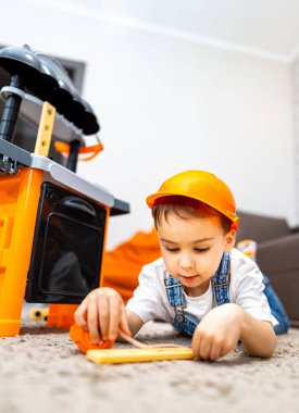 Çocuk kapalı mekan oyuncaklarıyla inşa ediyor. Genç bir çocuk, oyuncak bir inşaat setiyle yaratıcı bir oyun oynuyor, güvenlik şapkası takıyor ve kapalı alanda eğleniyor..