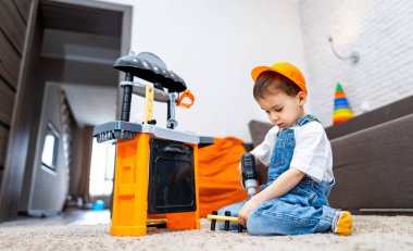 Çocuk oyuncak setiyle oynuyor. Genç bir çocuk, gündüz vakti evlerinde rahat bir yaşam alanına kurulmuş oyuncak bir inşaata odaklanıyor..