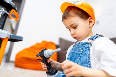 Çocuklar inşa ediyormuş gibi yapmayı sever. Sert şapkalı bir çocuk oyuncak matkap kullanır. Kapalı bir alanda yaratıcı oyun ve inşaat becerileri keşfeder..