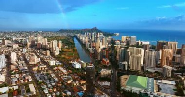 Waikiki tatil bölgesini şehir merkezinden ayıran Ala Wai Kanalı 'na yaklaşıyoruz. Gökkuşağı gökyüzünden Diamond Head Krateri 'ne iniyor. Oahu, Hawaii, ABD hava manzaralı.