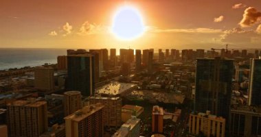 Gökyüzünü turuncuya boyayan muhteşem sıcak güneş. Honolulu, Hawaii, ABD 'de gün batımı zamanı. Güzel şehir manzarasının üzerindeki drone görüntüleri.