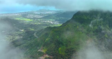 Otobandan geçen görkemli yeşil dağların üzerinden görüntüler. Honolulu, Hawaii, ABD 'nin şehir manzarası. Manzarayı kaplayan bulut manzarası. Üst görünüm.
