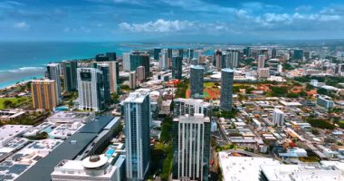 Waikiki, Honolulu, Hawaii, ABD 'deki yüksek binaların üzerinden uçuyor. Gök mavisi su manzarası ve bulutlu gökyüzü arka planda. Hava görünümü.
