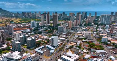 Yoğun bir şekilde inşa edilmiş Honolulu, Hawaii, ABD 'nin üzerinde uçuyor. Pasifik Okyanusu 'nun arka planında su manzarası. Martı İHA 'nın önünde uçar.