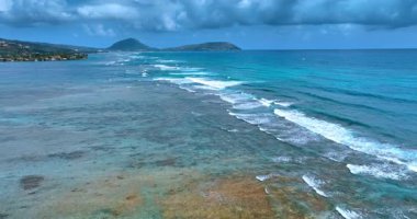 Alçak köpüklü dalgalar kıyı şeridine doğru akıyor. Gökyüzünü kaplayan yağmur bulutları. Hawaii yakınlarında Pasifik Okyanusu, ABD.