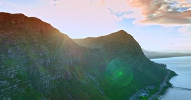 Parlak güneş, ayaklarının dibinde otoban olan devasa çıplak kayanın manzarasını kamaştırıyor. Kayalık sahildeki yerleşim alanının üstündeki insansız hava aracı görüntüleri. Hawaii, ABD.