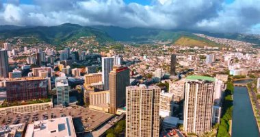Sunny Honolulu, Hawaii, ABD merkezindeki yüksek binaların üzerinde yükseliyor. Şehir manzarası ve muhteşem dağların üzerinde asılı ağır bulutlu bir manzara..