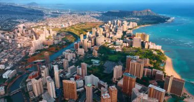 Ortasında yeşil park olan güzel lüks Waikiki tatil köyü. Ala Wai Kanalı ve Pasifik Okyanusu çevreyi sarar. Diamond Head Krateri arka planda. Hava görünümü.