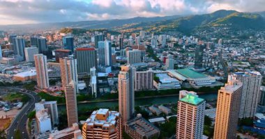 Gün batımında, Honolulu, Hawaii 'nin şehir manzarası. Arkaplanda yeşil yamaçlı bir dağ sırası. Gökyüzündeki kara bulutlar. Hava görünümü.