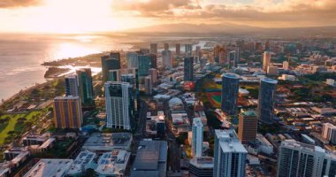 Honolulu, Hawaii, ABD 'nin çeşitli şehir manzarasının üzerinde gün batımı. Güzel bulutlar ve arka planda yumuşak ışıktaki dağ siluetleri. Hava görünümü.