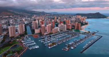 Yat kulübüne çok sayıda araçla daha yakın uçuyorlar. Waikiki, Honolulu, Hawaii, ABD 'ye hava kararınca yaklaşıyoruz. Arka planda gökyüzünü kaplayan kalın bulutlu bir manzara. Hava görünümü.