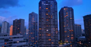 Çok katlı binaların pencerelerinde ışık yandı. Honolulu, Hawaii, ABD 'de alacakaranlık vakti. İnsansız hava aracı görüntüleri.
