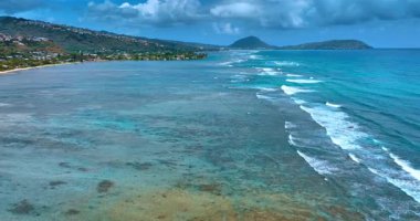 Pasifik Okyanusu kıyısı boyunca uçuş. Küçük dalgalar sahile doğru akıyor. Arkaplanda Honolulu 'nun resimli rıhtımı.