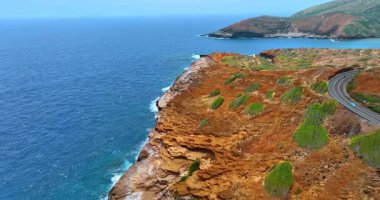 Kaya kıyısı su ve rüzgarla kavrulmuş. Nakliye kıyıya yakın otobanda ilerliyor. Hawaii 'deki Pasifik Okyanusu kıyısı.