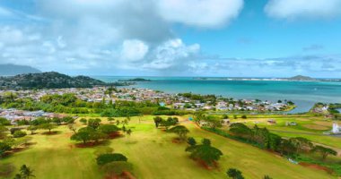 Pasifik Okyanusu kıyısında güneş ışığında golf sahası. Arka planda yoğun bir yerleşim alanı var. Honolulu, Hawaii, ABD.