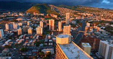 Batan güneşin turuncu ışığında Honolulu 'nun değişik manzaraları. Dağların üzerinden dramatik kara bulutlar geliyor. Hava görünümü.