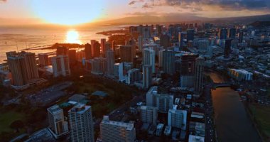 Pasifik Okyanusu şehri turuncu batan güneşle aydınlatılır. Waikiki ve Ala Wai Kanalı üzerinde İHA görüntüleri. Hava görünümü.