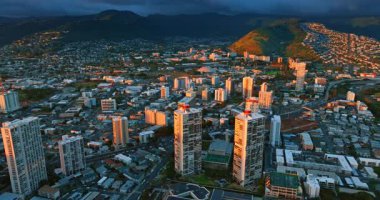 Honolulu, Hawaii, ABD 'nin çeşitli şehirlerinden aşağı iniyor. Dağların üzerinde kara bulutlar asılı..