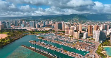 Waikiki rıhtımındaki çapada bir sürü yat duruyor. Bulutlu gökyüzünün altında güneşli bir Honolulu, Hawaii manzarası. Hava görünümü.