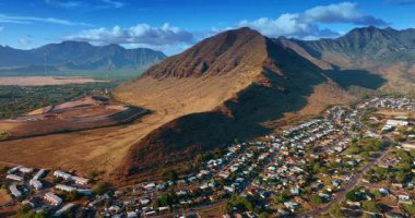 Engebeli yamaçları olan görkemli çıplak kayalara yaklaşıyoruz. Dağların eteklerine dağılmış birden fazla evi olan yerleşim yerleri. Hava görünümü.