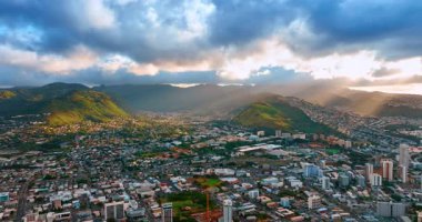 Dağların arasına dağılmış yüksek nüfuslu şehrin muhteşem manzarası. Batan güneş ışınları bulutların arasından geçer. Hava perspektifi.