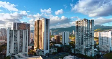 Waikiki, Honolulu, Hawaii, ABD 'deki çok katlı apartman blokları boyunca yükseliyor. Arkadaki mavi gökyüzünde güzel pofuduk bulutlar.