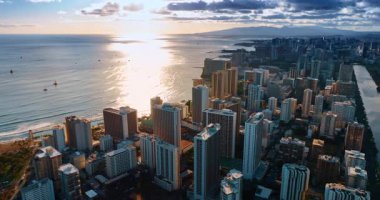 Pasifik Okyanusu 'nun manzarası batan güneşin ışığını yansıtıyor. Bazı tekneler okyanus kıyısında yelken açar. Waikiki, Honolulu, Hawaii, ABD 'de insansız hava aracı görüntüleri yükseliyor..