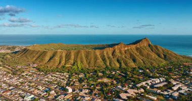 Diamond Head Krateri 'nin engebeli yamaçları parlak güneşle aydınlanır. Kayanın etrafındaki Honolulu şehri. Hava görünümü.