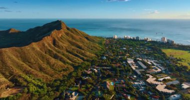 Diamond Head Krateri 'nin eteğindeki yemyeşil alanda şehrin üzerinde uçmak. Honolulu, Hawaii, ABD. Arkaplanda Pasifik Okyanusu manzarası.