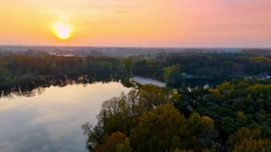 Hollanda 'da huzurlu bir gün batımı. Altın gün batımı, Hollanda 'daki yemyeşil ve yumuşak tepelerle çevrili sakin göle yansıyor..