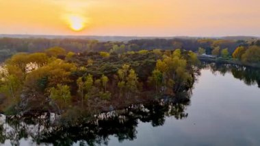 Hollanda 'da sakin bir gün batımı. Bereketli yeşilliklerin çerçevelediği sakin sularda sakin bir günbatımı Hollanda 'daki doğanın güzelliğini gözler önüne seriyor..