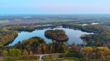 Serene Dutch manzara havası. Hollanda 'da dingin bir su kütlesi çevreleyen canlı yeşillik, gün batımında doğal güzellikleri gözler önüne seriyor..