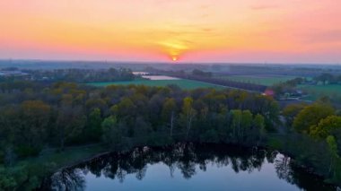 Hollanda tarlalarında bahar günbatımı. Güneş, Hollanda 'nın canlı yeşil tarlaları ve ormanlık alanlarında doğanın renklerini gözler önüne sererek batıyor..