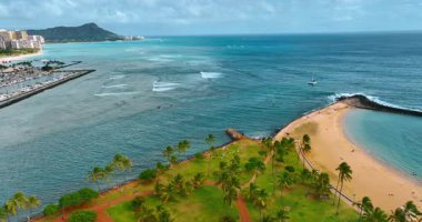 Palmiye ağaçları ve kumlu plajlarla yeşil çimlerin üzerinde uçarak Pasifik Okyanusu 'nun sularına yaklaşıyorlar. Diamond Head Krateri arka planda. Oahu, Hawaii, ABD.