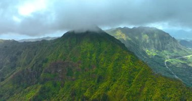 Dağların tepelerinde hareket eden kalın bulutlar. Kertenkelelerle kaplı yüksek kayaya havadan bakış açısı.