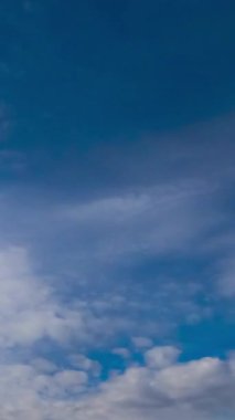 Yumuşak ışık bulutları ufukta hızla akıyor. Ağır gri bulutlar yumuşak bulutları değiştiriyor. Düşük açı. Zaman ayarlı. Dikey video