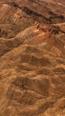 Mojave Çölü 'nün kahverengi kuru manzarası. Ortasında otoyol olan kayalık bir arazi. Üst Manzara. Dikey video
