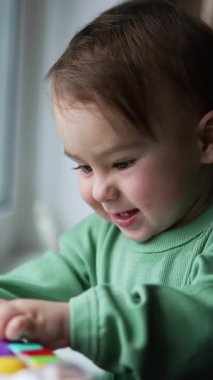 Küçük şirin çocuk oyuncaklarla oynuyor. Küçük bebek evde eğleniyor. Dikey video