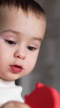 Kameraya oyuncak gösteren güzel beyaz bir bebek. Sevimli çocuk dikkatlice oyuncağa bakıyor. Kapatın. Dikey video