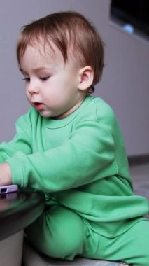 Evde oynayan küçük bir bebek. Bebek gibi mutlu bir çocuk. Dikey video