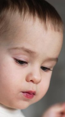 Beyaz bir bebeğin melek gibi tatlı bir yüzü var. Küçük çocuk kameraya dilini gösteriyor. Kapatın. Arkaplan bulanık. Dikey video