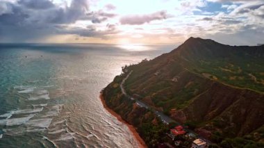 Engebeli dağ boyunca kraterli bir otoyol inşa edildi. Pasifik Okyanusu kıyıya doğru akar. Gökyüzünde kalın bulutlar. Honolulu, Hawaii, ABD. Hava görünümü.