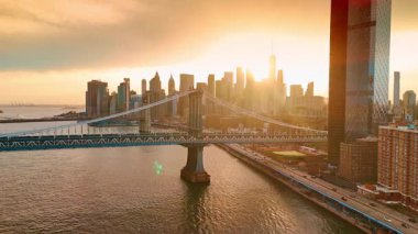 New York şehir merkezinin siluetleri parlak batan güneşle göz kamaştırıyordu. Doğu Nehri boyunca otobanlarda hareketli trafik. Hava görünümü.