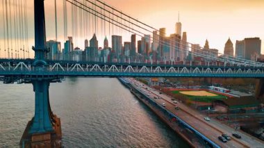 New York 'taki Manhattan Köprüsü' nün tepesine yükseliyor. Gökdelenlerin ardında güneş batıyor..