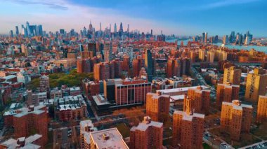 Batan güneş New York 'taki binaların turuncu cephelerini aydınlatıyor. Arkaplanda gökdelenler var. Hava görünümü.