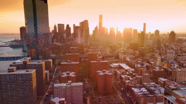 Gün batımında Manhattan manzarası. Şehir manzarası turuncu ışıktan göz kamaştırıyor. Manhattan Köprüsü ve Brooklyn Köprüsü 'ne hava perspektifi.