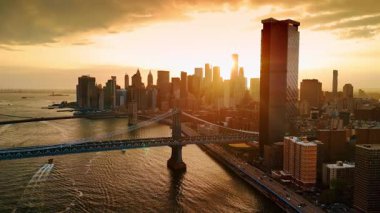 Gün batımında Manhattan 'ın silüeti. Manhattan Köprüsü boyunca Doğu Nehri üzerinde İHA uçuşu.