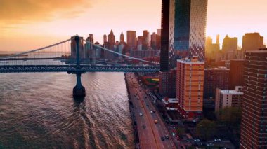 Doğu Nehri boyunca otobanlarda hareketli trafik. Manhattan Köprüsü boyunca insansız hava aracı görüntüleri ve rıhtımdaki binalar. New York 'ta günbatımı. Hava görünümü.