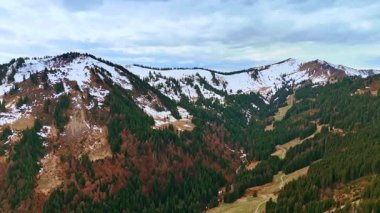 Yamaçlarında yeşil ve kuru çam ağaçları olan karla kaplı dağlar. Almanya ve Bavyera 'da insansız hava aracı görüntüleri.