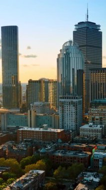 Boston şehir merkezindeki çeşitli ofis kuleleri ve gökdelenler. Tepeden güzel manzaranın üstünde uçmak... dikey video.